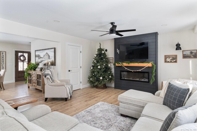 living room with ceiling fan, a fireplace, and light hardwood / wood-style floors