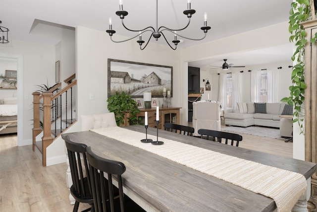 dining room with ceiling fan with notable chandelier and light hardwood / wood-style flooring