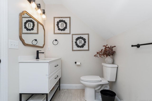 bathroom with vanity, lofted ceiling, wood-type flooring, and toilet