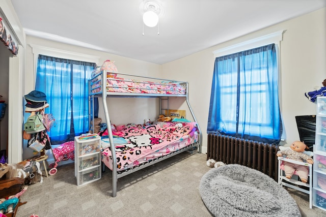 carpeted bedroom with ceiling fan and radiator heating unit