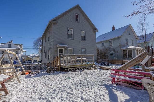 snow covered rear of property with a deck