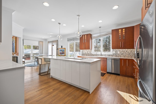 kitchen with pendant lighting, appliances with stainless steel finishes, a center island, and light wood-type flooring