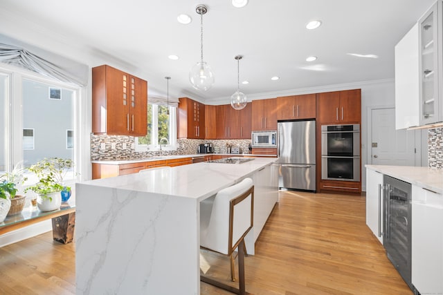 kitchen featuring stainless steel appliances, a center island, pendant lighting, and light hardwood / wood-style flooring