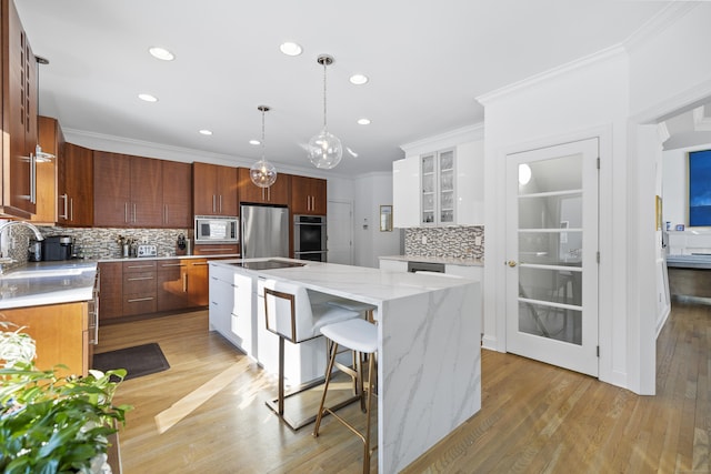 kitchen with white cabinets, appliances with stainless steel finishes, a large island, and backsplash