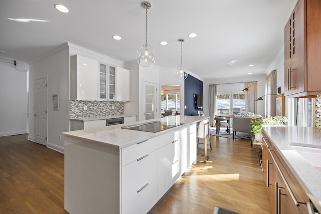 kitchen featuring light stone counters, a center island, ornamental molding, white cabinets, and backsplash