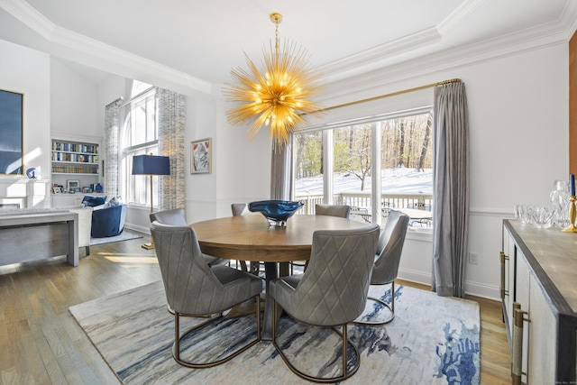 dining room with ornamental molding, hardwood / wood-style floors, built in features, and a chandelier