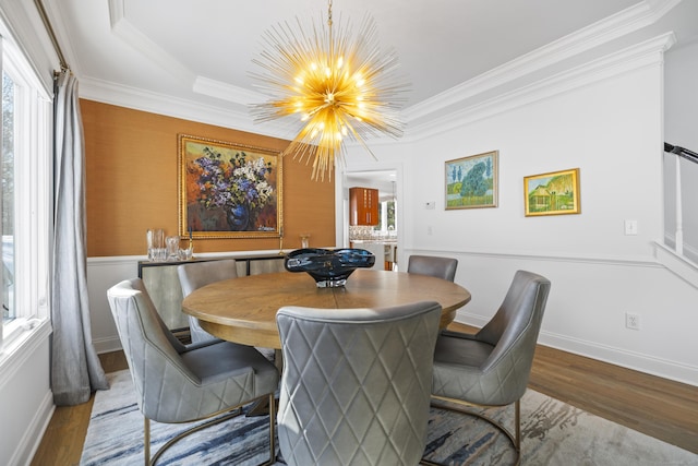 dining space with hardwood / wood-style flooring, ornamental molding, and a notable chandelier