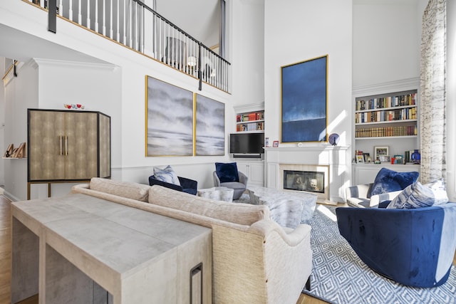 living room featuring crown molding, built in features, and a tile fireplace