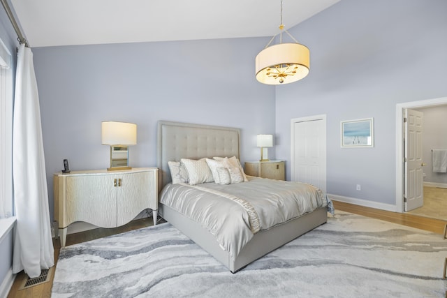 bedroom with hardwood / wood-style flooring and high vaulted ceiling