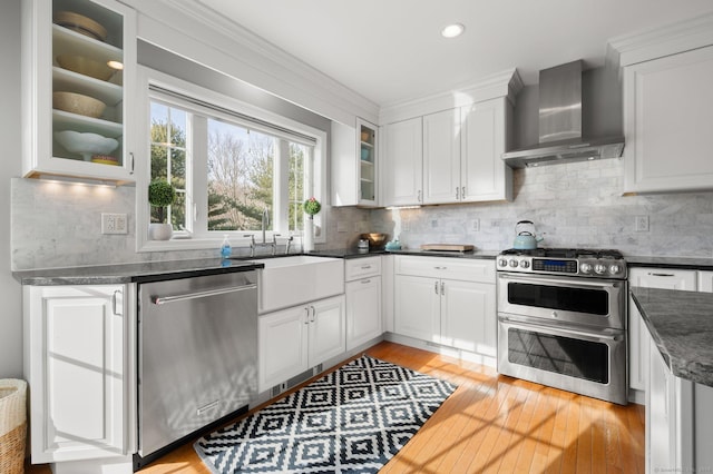 kitchen featuring white cabinetry, tasteful backsplash, wall chimney exhaust hood, and appliances with stainless steel finishes