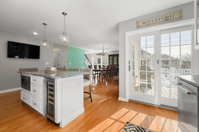 kitchen with light hardwood / wood-style flooring, wine cooler, white cabinets, built in microwave, and decorative light fixtures