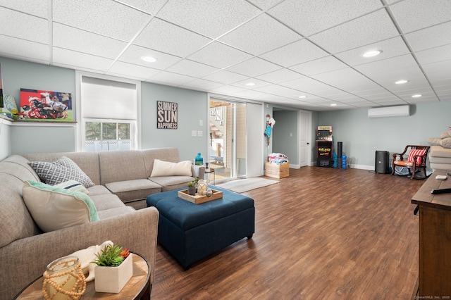 living room featuring a paneled ceiling, dark wood-type flooring, and a wall mounted AC