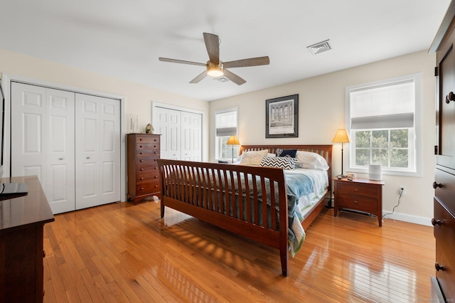 bedroom with two closets, ceiling fan, and light hardwood / wood-style flooring