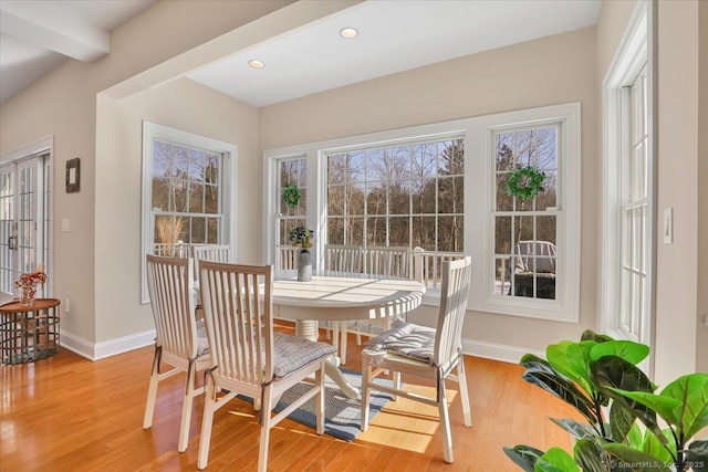 dining area with beamed ceiling and light hardwood / wood-style floors