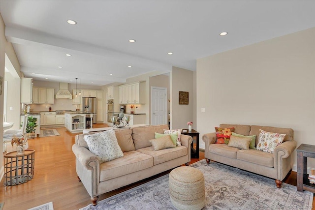 living room featuring sink and light hardwood / wood-style flooring