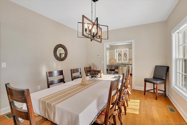 dining room featuring an inviting chandelier, a healthy amount of sunlight, and light hardwood / wood-style flooring