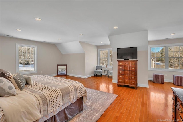 bedroom featuring radiator, light hardwood / wood-style floors, and multiple windows