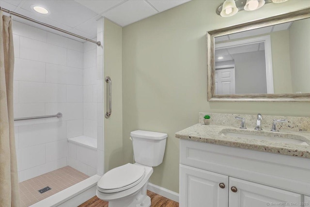 bathroom featuring hardwood / wood-style flooring, vanity, toilet, and a tile shower