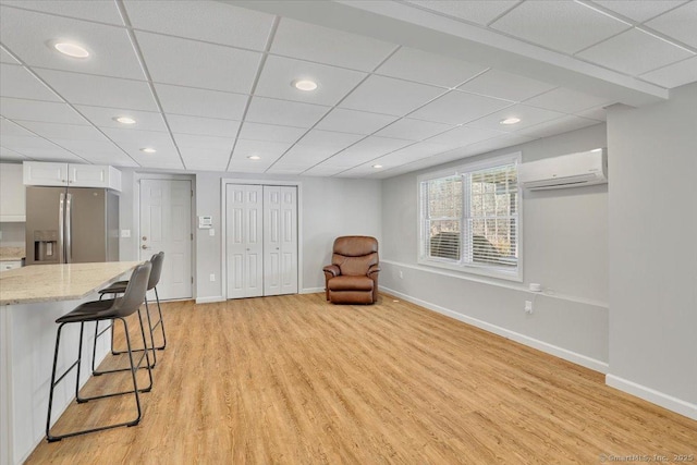 sitting room with a wall mounted AC and light wood-type flooring