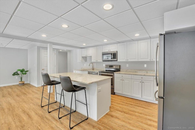 kitchen featuring a kitchen island, sink, white cabinets, a kitchen breakfast bar, and stainless steel appliances