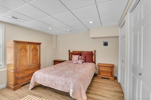 bedroom featuring a drop ceiling, light hardwood / wood-style flooring, and a closet