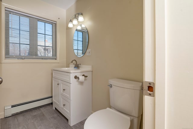 bathroom featuring vanity, a baseboard heating unit, and toilet