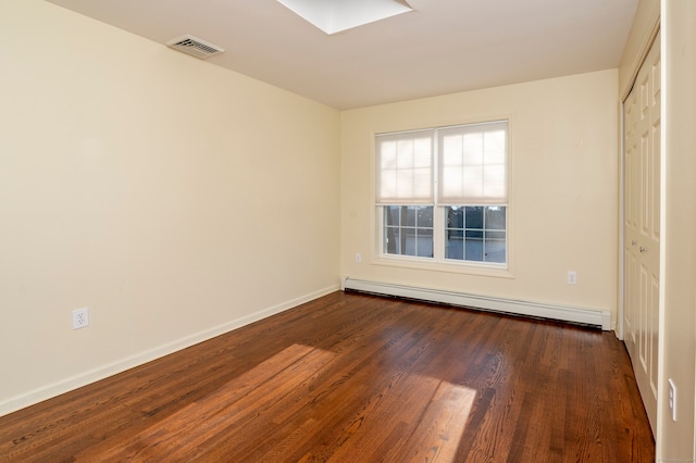 empty room with a baseboard radiator and dark hardwood / wood-style flooring