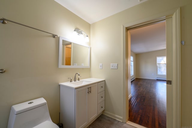 bathroom with hardwood / wood-style flooring, vanity, a baseboard heating unit, and toilet