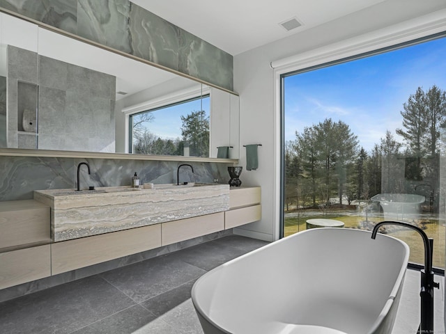 bathroom with visible vents, a freestanding bath, and vanity