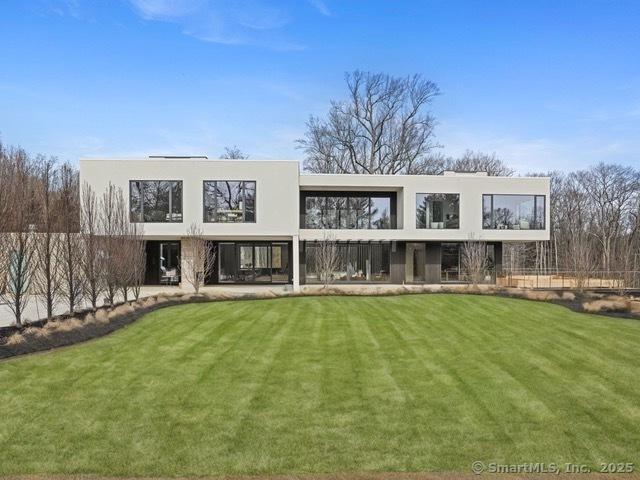 rear view of house with stucco siding and a yard