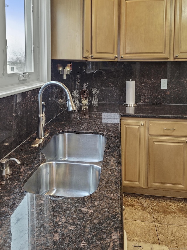 kitchen featuring sink, dark stone countertops, and backsplash