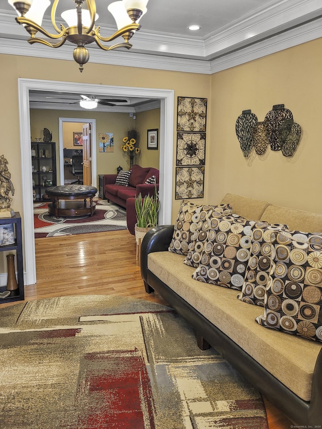 living room featuring an inviting chandelier, ornamental molding, a raised ceiling, and wood-type flooring