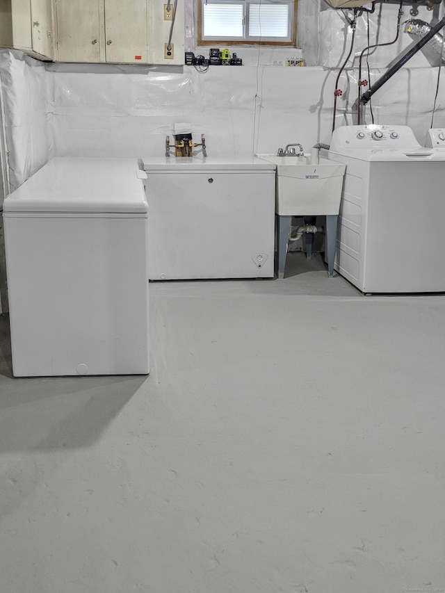 laundry area with cabinets, washer and clothes dryer, and sink