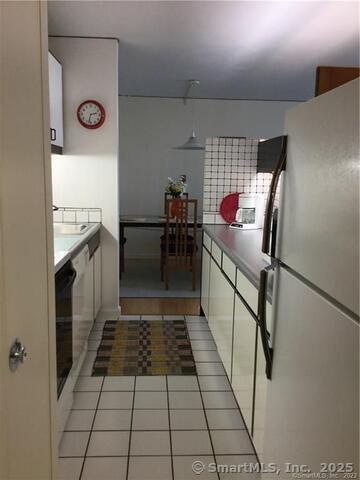 kitchen featuring white cabinetry, sink, light tile patterned floors, and refrigerator