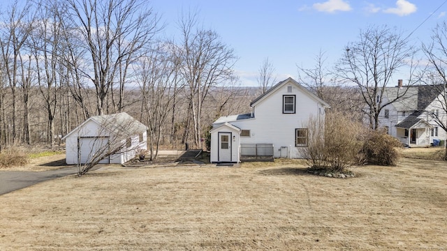 rear view of house featuring a detached garage and an outdoor structure