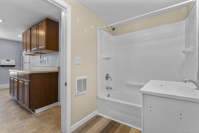 bathroom with vanity, wood finished floors, washtub / shower combination, and baseboards