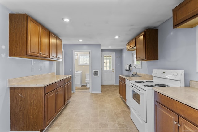 kitchen featuring white appliances, brown cabinetry, light countertops, and a sink