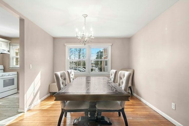 dining room with a chandelier, plenty of natural light, and light wood-style flooring