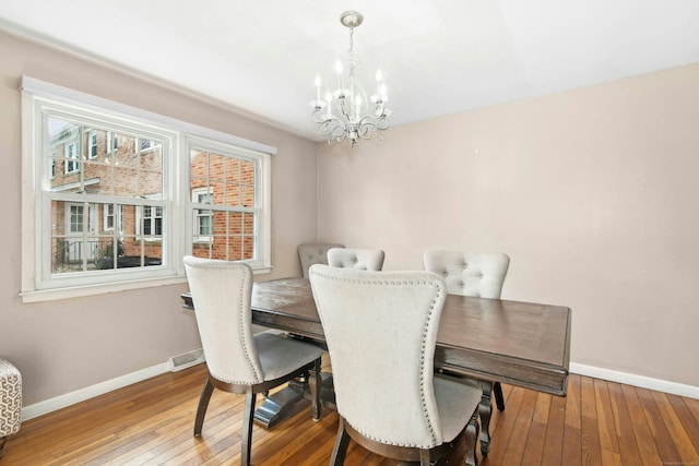 dining area featuring a chandelier, visible vents, hardwood / wood-style floors, and baseboards