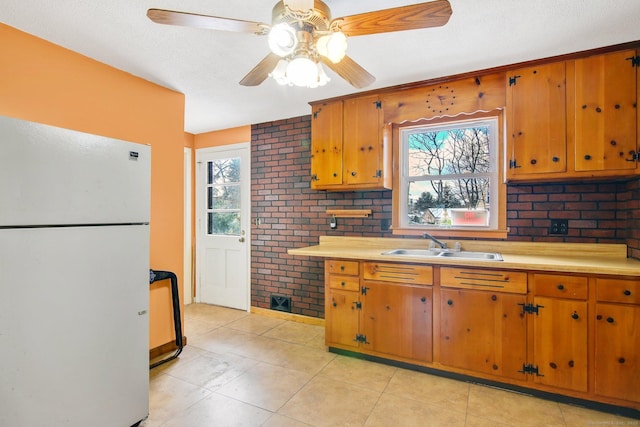 kitchen featuring plenty of natural light, sink, white refrigerator, and light tile patterned floors