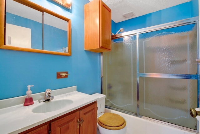 full bathroom with toilet, bath / shower combo with glass door, vanity, and a textured ceiling