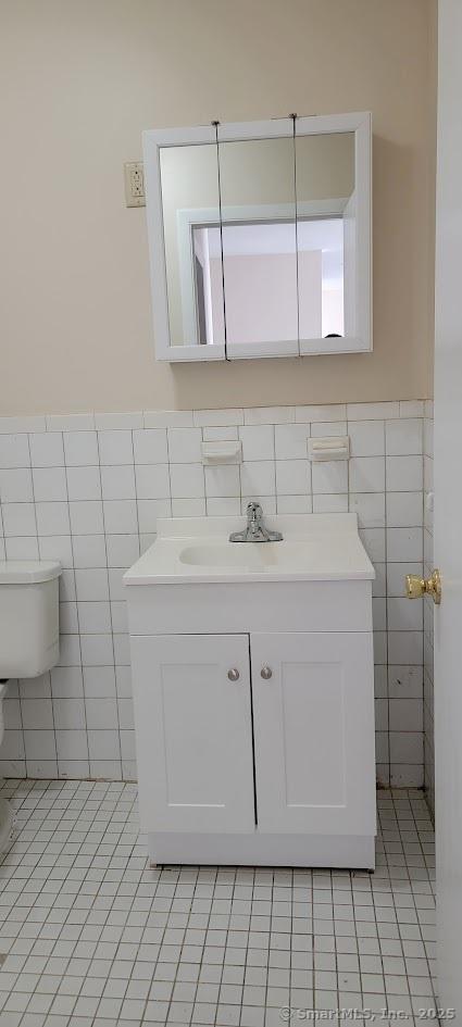 bathroom with tile patterned flooring, vanity, and tile walls