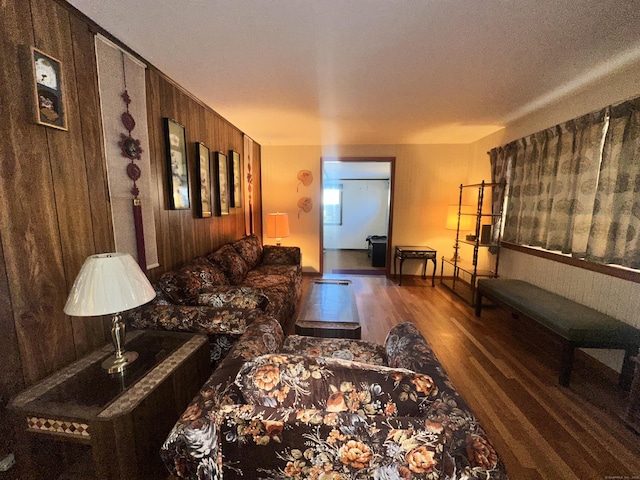 living room with dark hardwood / wood-style flooring and wood walls