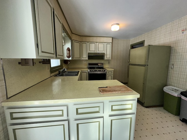 kitchen with gas stove, sink, stainless steel refrigerator, and kitchen peninsula