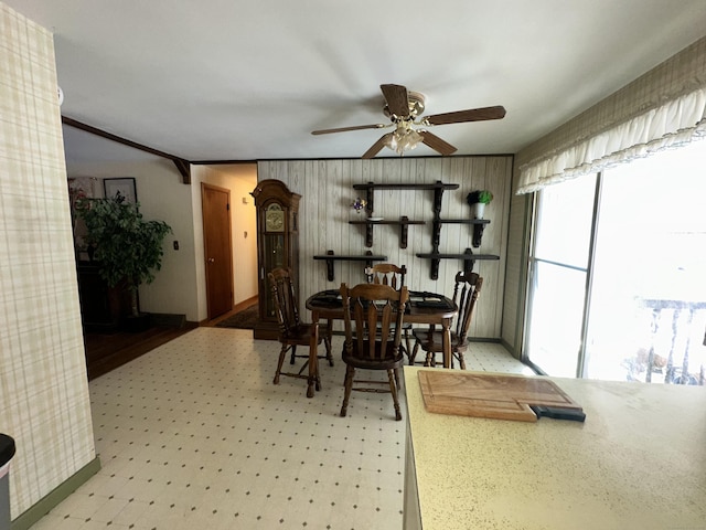 dining space featuring ceiling fan and wood walls