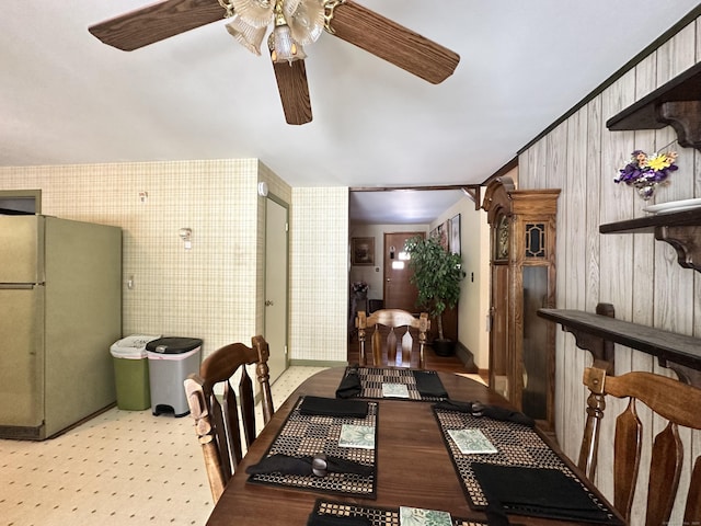 dining area featuring wooden walls and ceiling fan