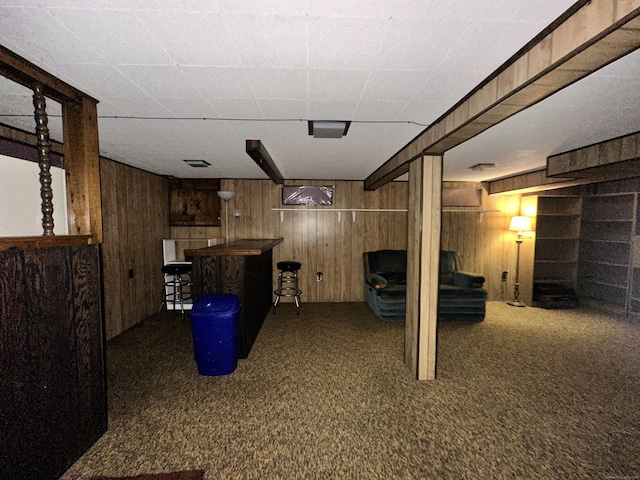 basement with dark carpet and wood walls