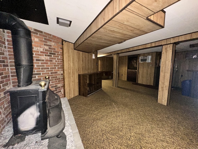 basement featuring a wood stove, carpet, and wood walls