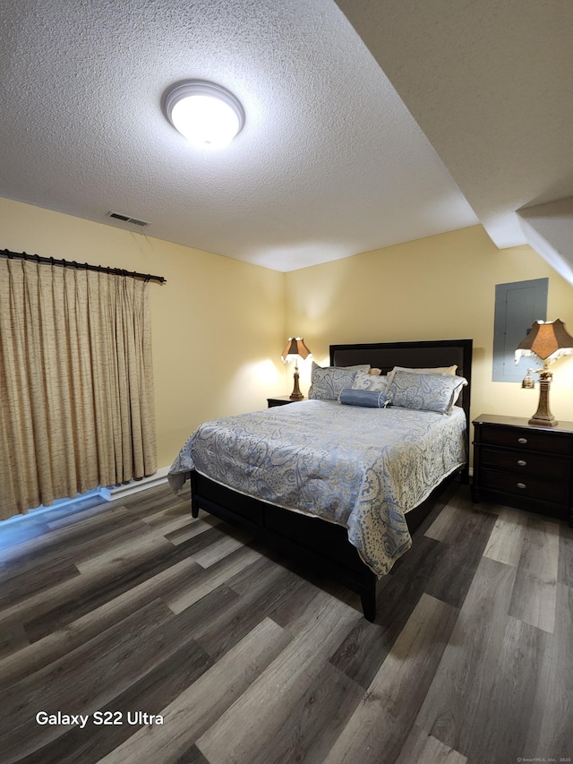 bedroom featuring a textured ceiling and dark hardwood / wood-style flooring