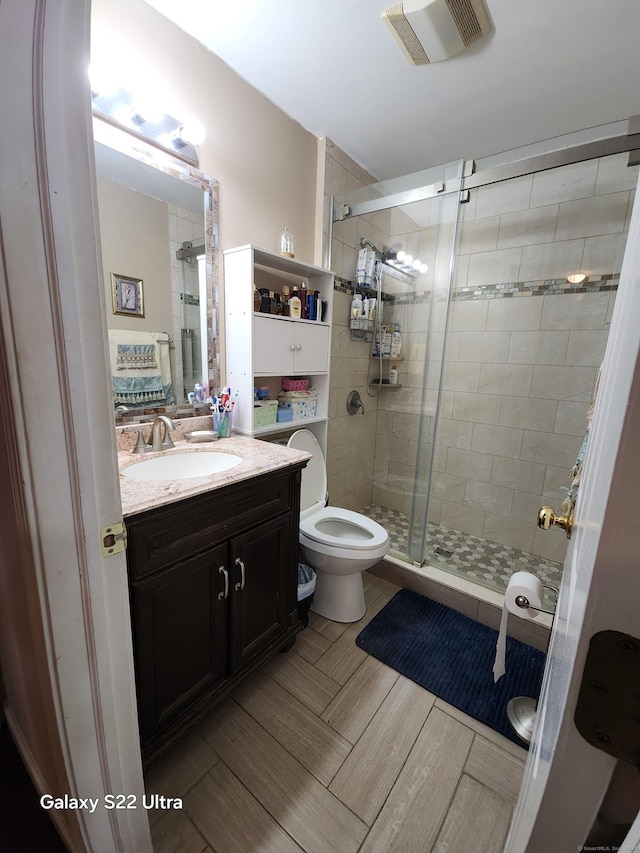 bathroom featuring walk in shower, vanity, and toilet